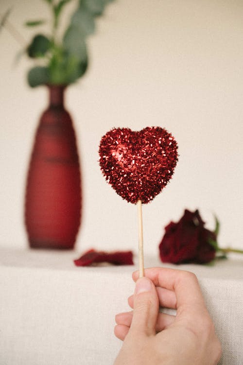Hand Holding Red Lollipop in Heart Shape