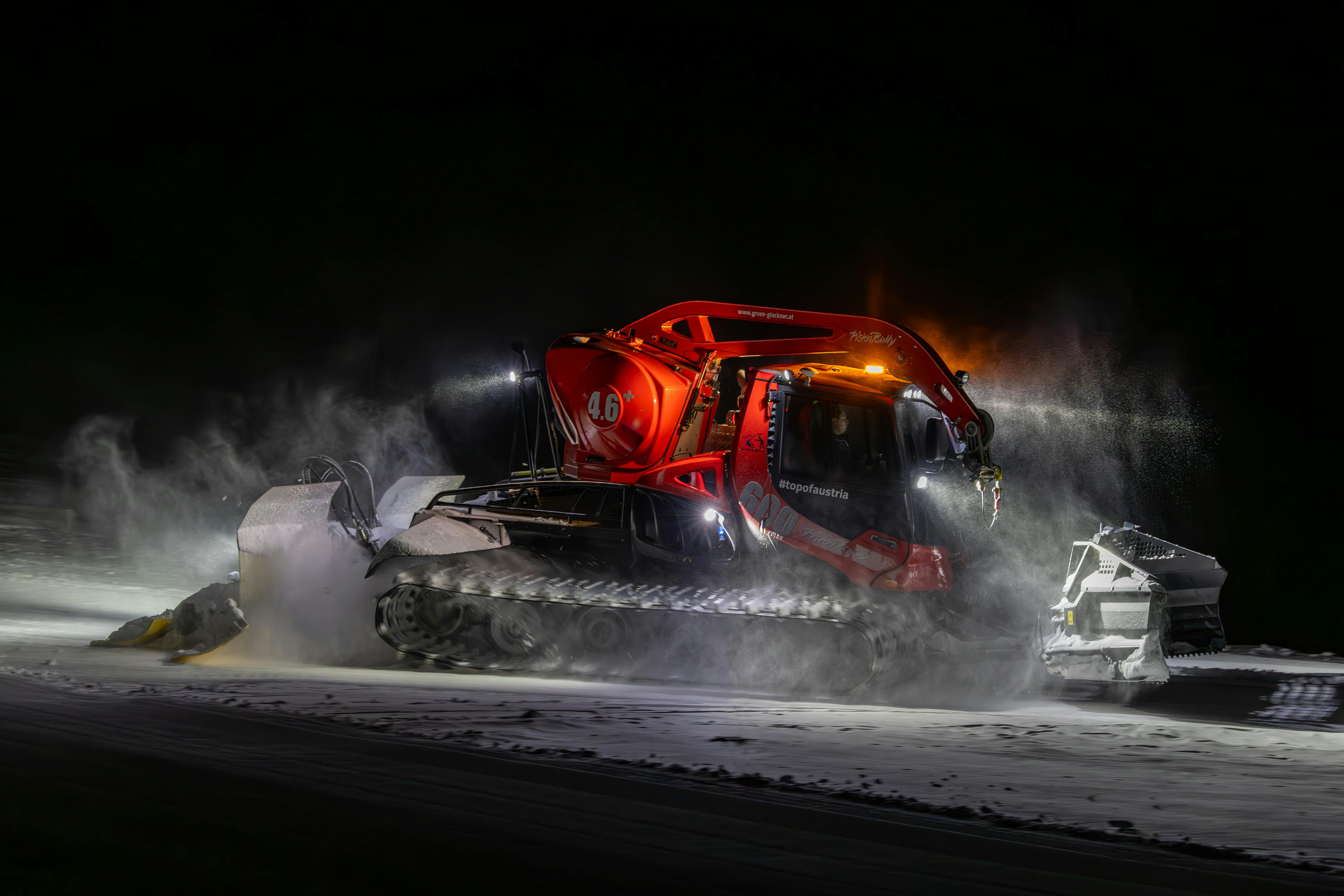 Powerful snow groomer in action at night, preparing ski slopes with precision.