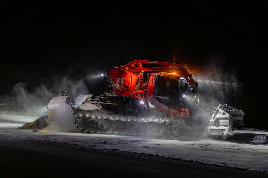 Powerful snow groomer in action at night, preparing ski slopes with precision.