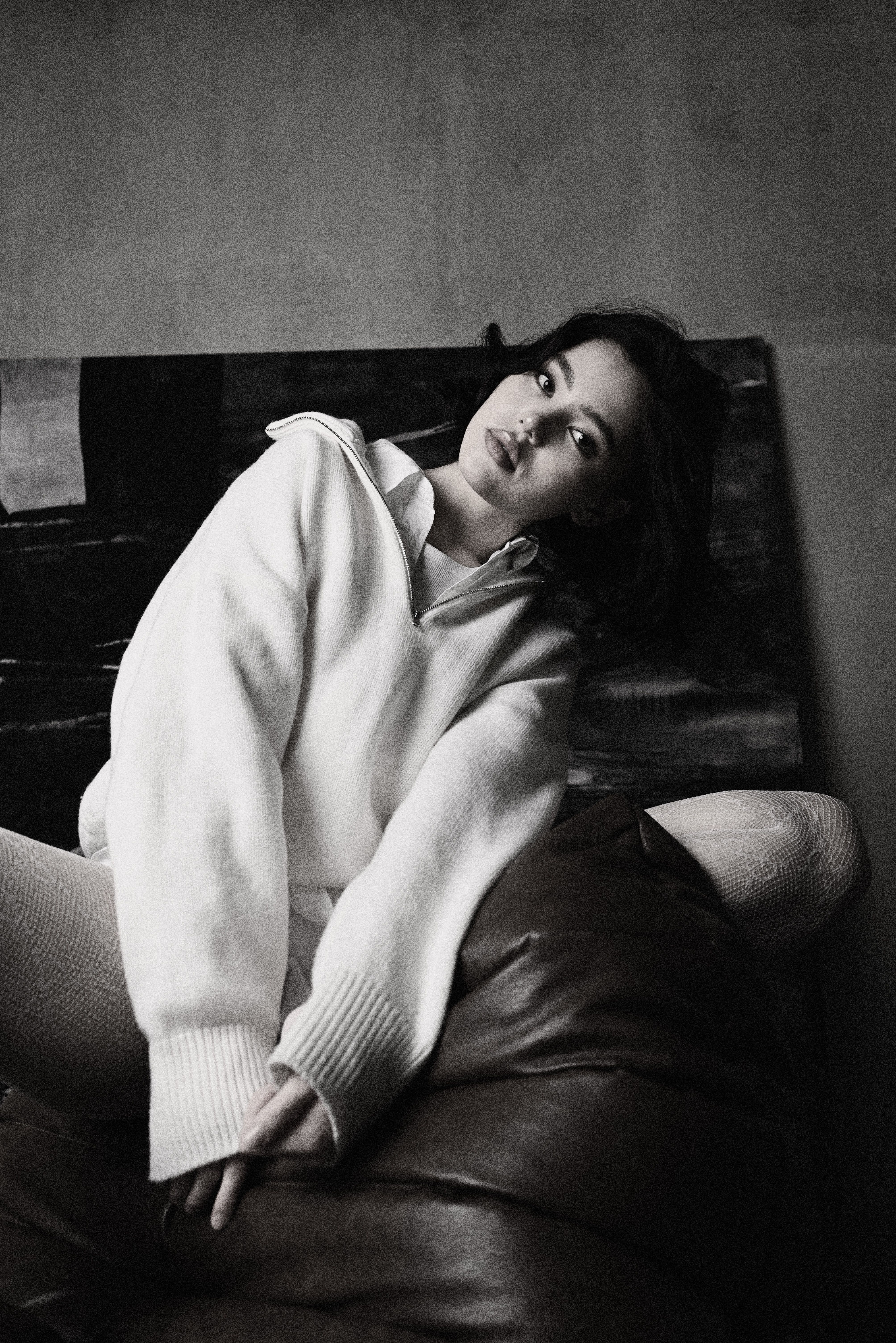A woman in a white sweater sitting on a couch · Free Stock Photo
