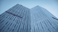 在晴朗的蓝天下，从低视角拍摄现代玻璃摩天大楼，捕捉城市建筑设计