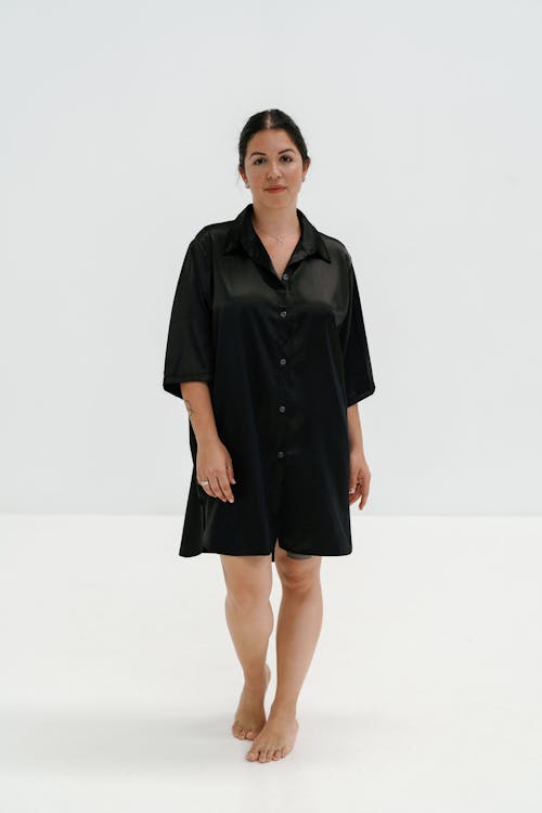 A woman in a black shirt dress and black sandals