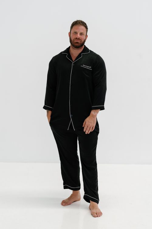 Free Adult man in black pajamas stands on white background, showing casual fashion. Stock Photo