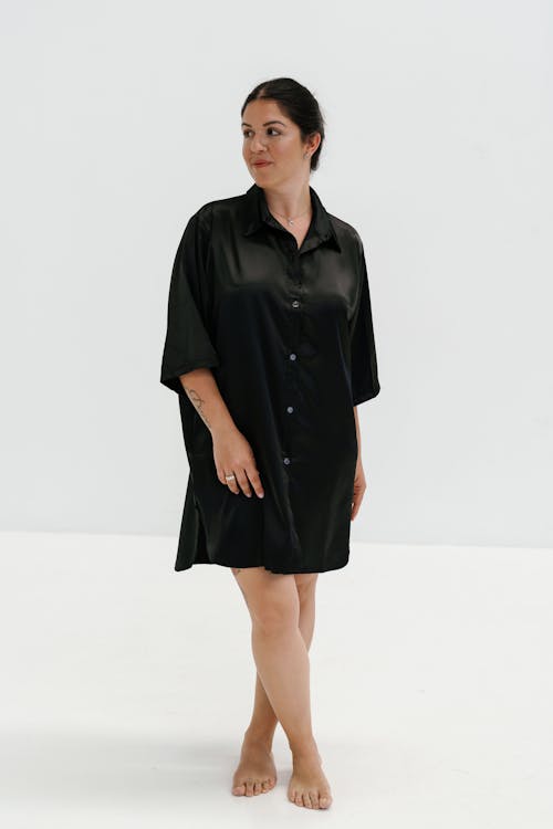 A woman in a black shirt dress poses for a photo