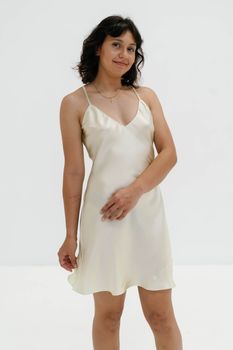 A woman wearing a sleek satin dress posing confidently against a neutral backdrop.