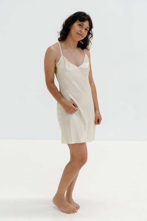 The model is wearing a white silk slip dress