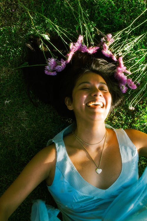 Free Happy Brunette Woman Lying on Grass by Pink Flowers Stock Photo