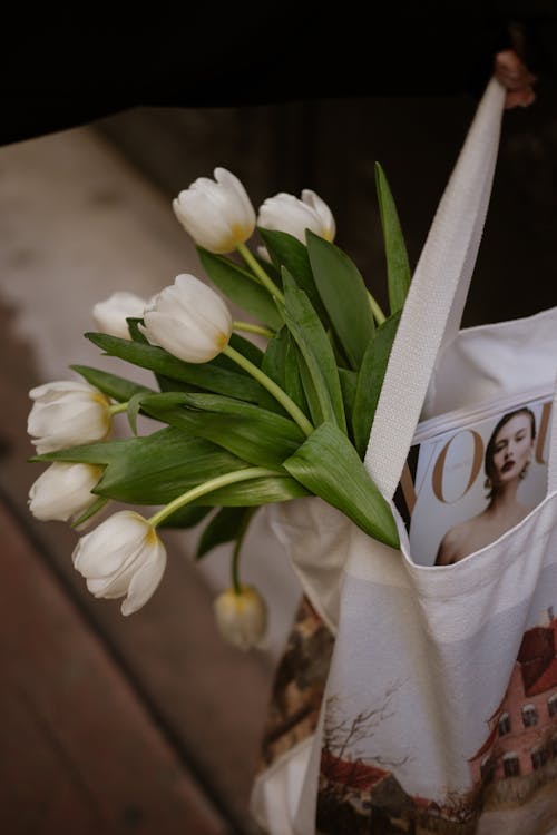 A woman holding a tote bag with white tulips