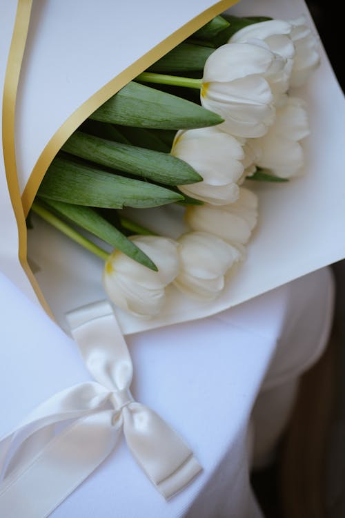 A bouquet of white tulips with a ribbon