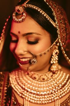 Close-up of an Indian bride adorned in golden jewelry and traditional attire, showcasing cultural elegance.