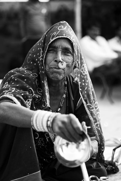 Elderly Woman in a Headscarf and Jewelry Sitting Outside 