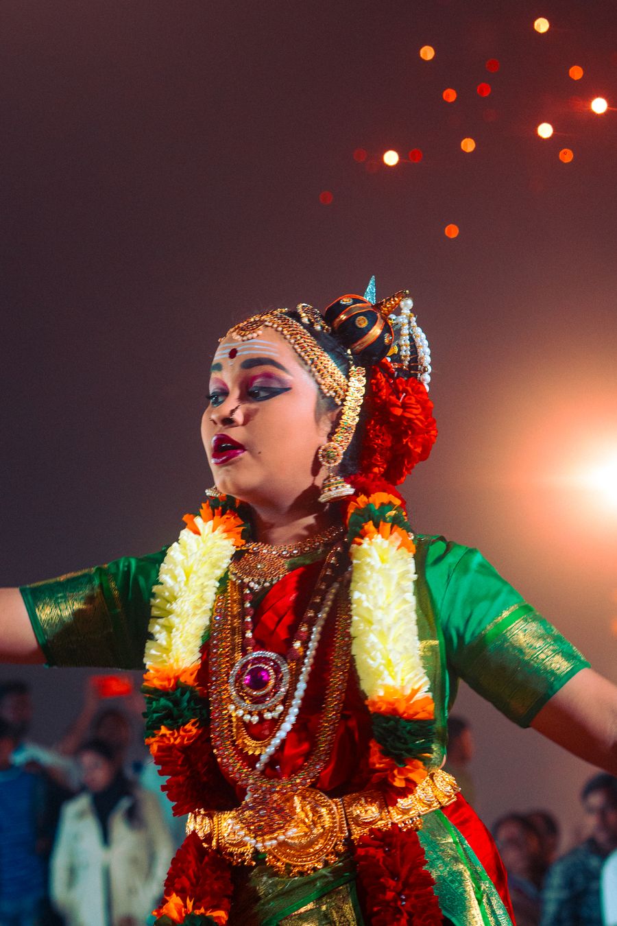 Classical dancer with a garland performing under festive lights