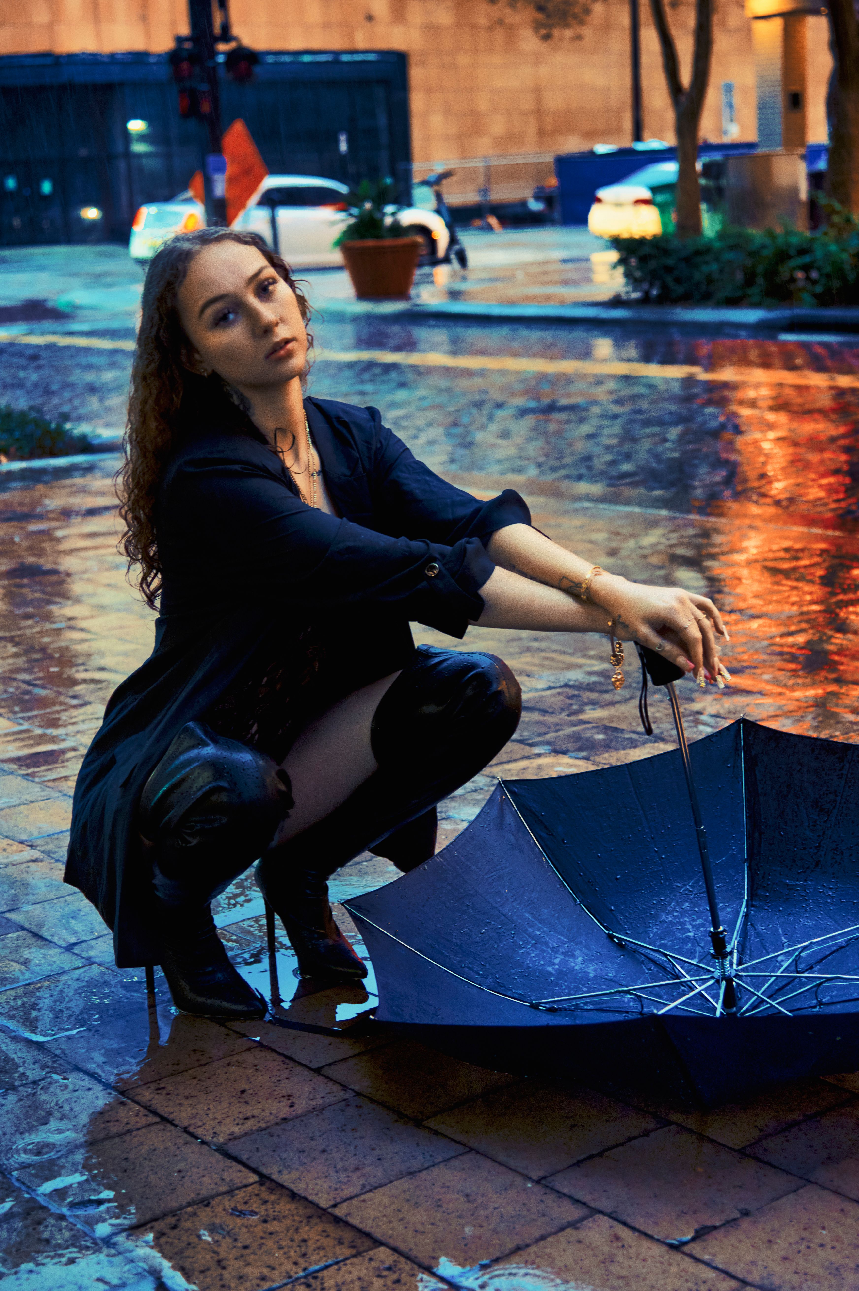 Woman in elegant trench coat holding umbrella on rainy street