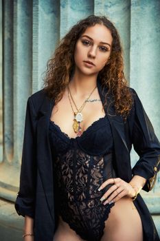 Chic portrait of a woman in a black lace bodysuit and jacket, showcasing modern fashion.