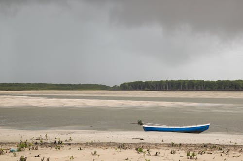 A boat is sitting on the beach under a cloudy sky