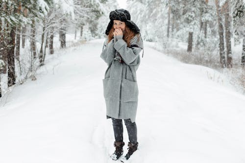 A Beautiful Woman with Her Hands Near Mouth Standing on Snow Covered Ground