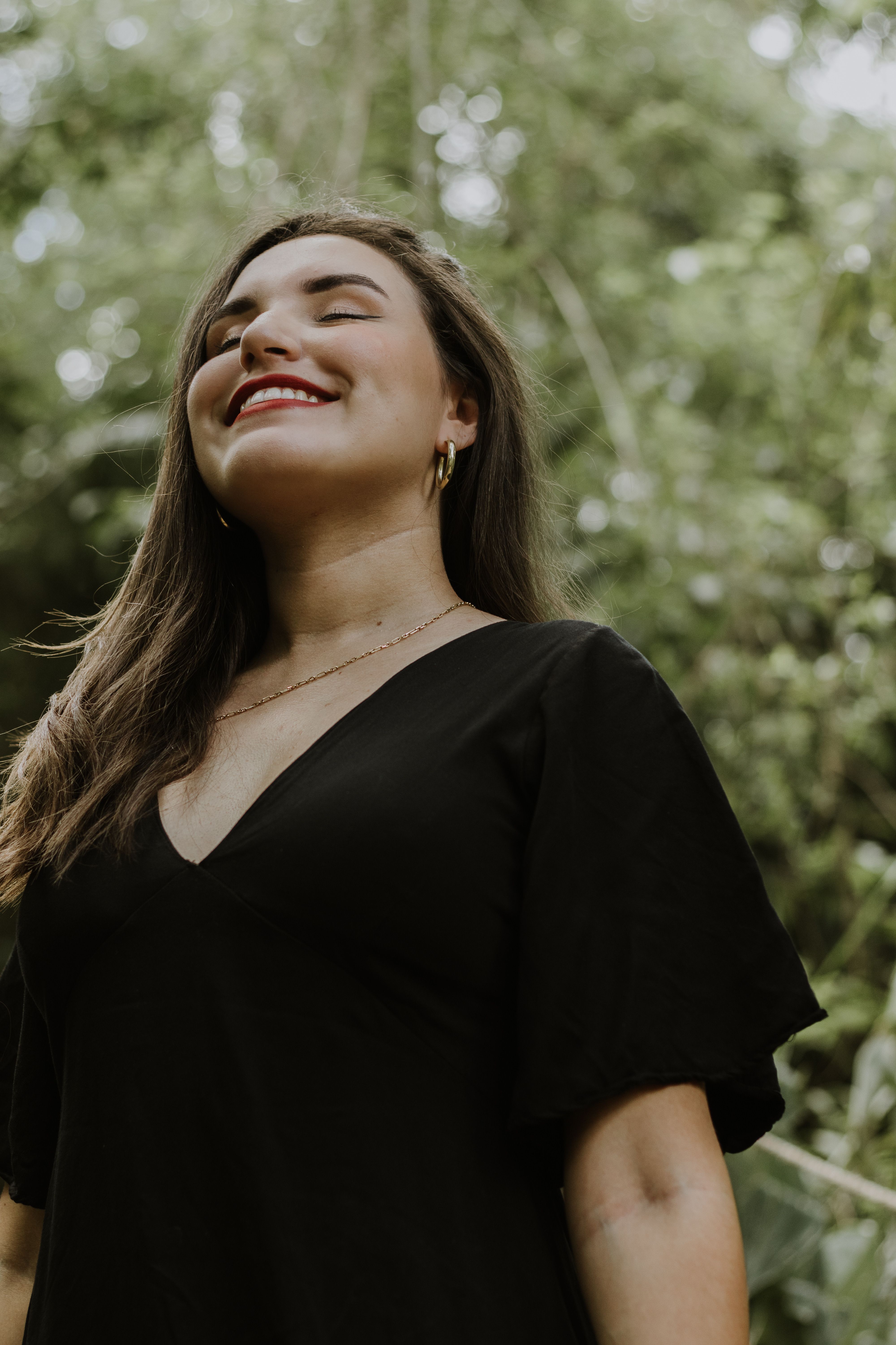 Brunette Woman in Black Dress Smiling in Park · Free Stock Photo