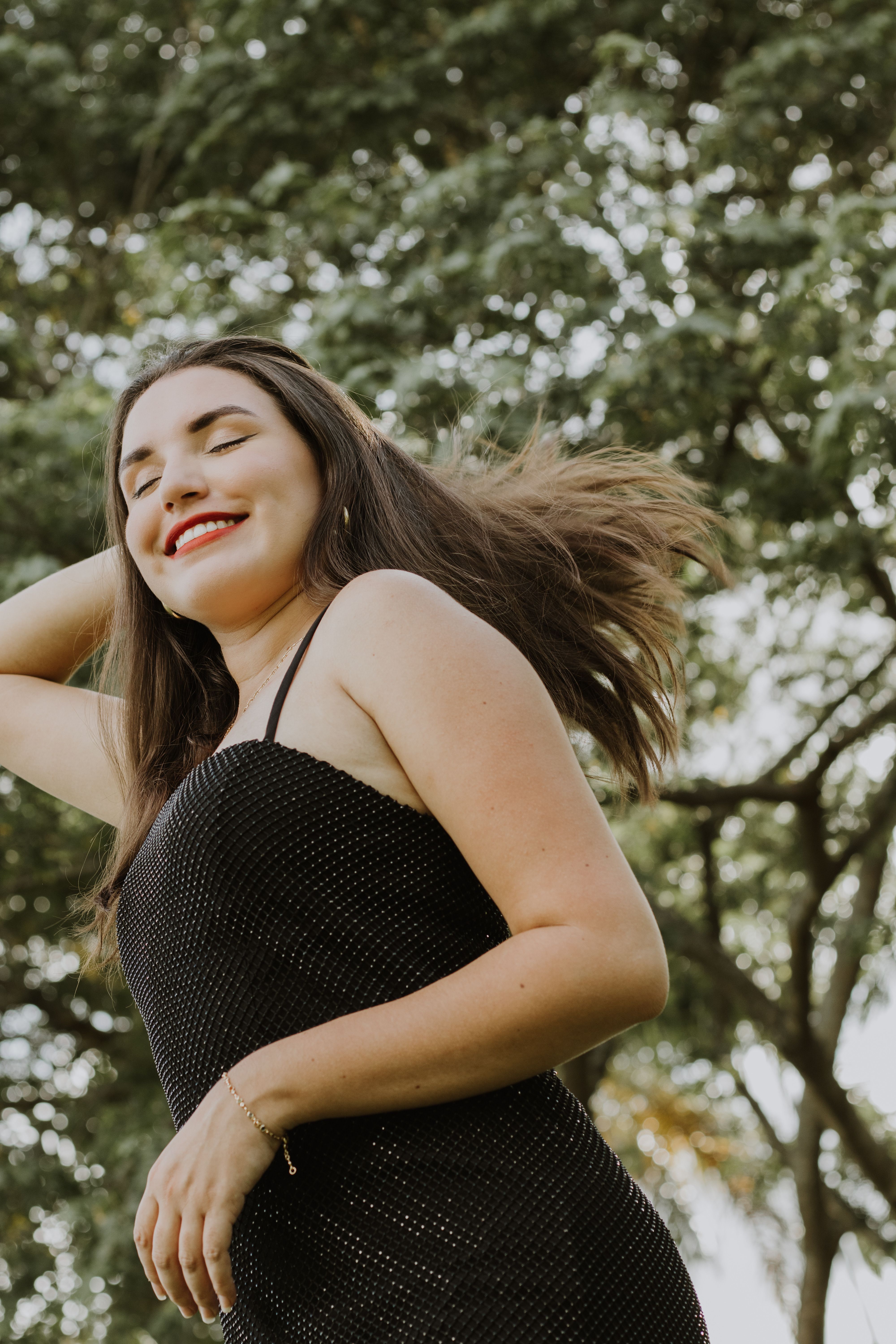 Brunette Woman in Black Dress Smiling in Park · Free Stock Photo