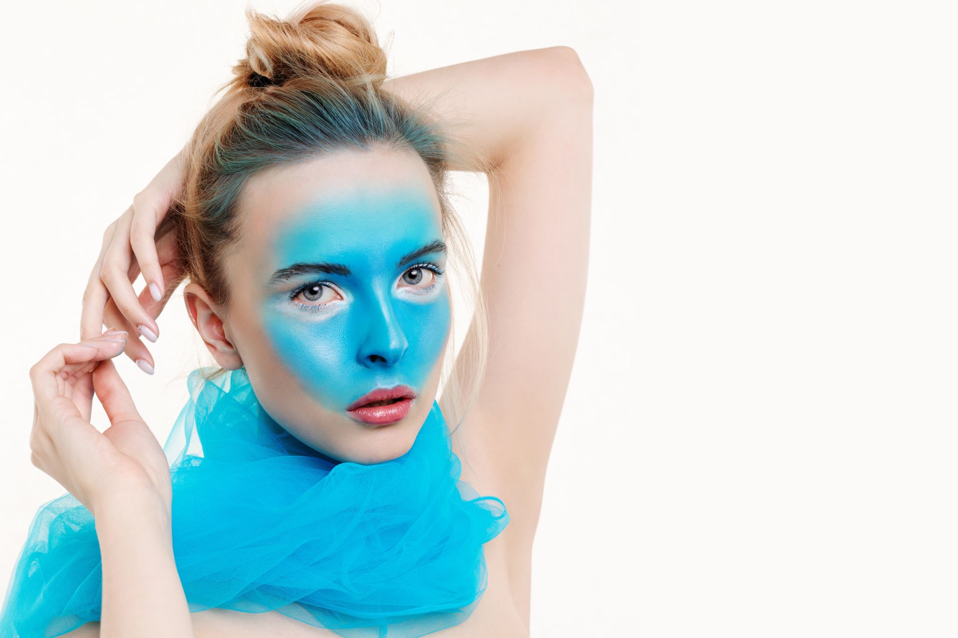 Elegant portrait of a woman with blue face paint and scarf against a light background.