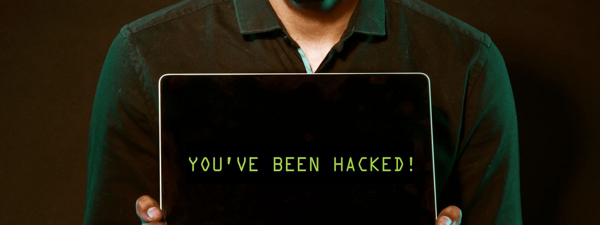Hombre mostrando un portátil con un aviso de hackeo