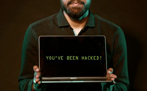 Hombre mostrando un portátil con un aviso de hackeo