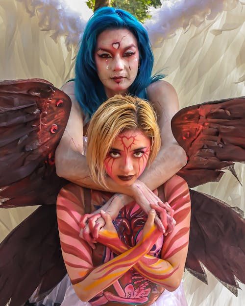 Two women with angel wings and blue hair