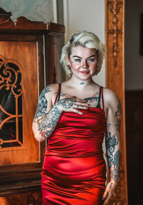 A woman with tattoos posing in a red dress