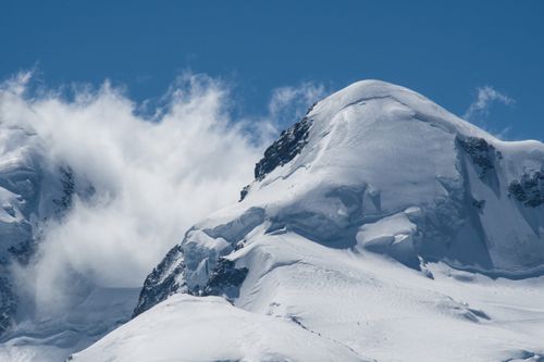 Free Breathtaking view of snowy peaks in Zermatt with swirling clouds and deep blue sky. Stock Photo
