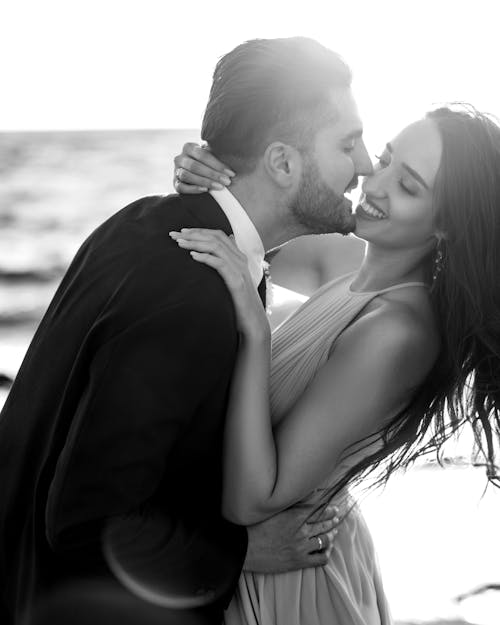 Smiling Newlyweds Kissing at Sunset in Black and White