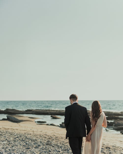 A bride and groom walking along the beach