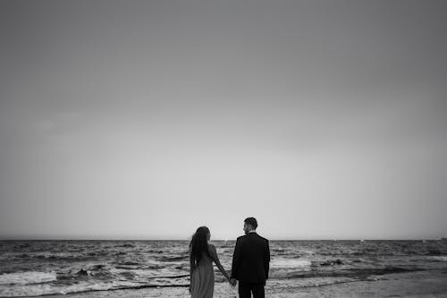 A black and white photo of a couple standing on the beach