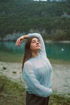 Woman enjoys peaceful meditation near a tranquil lake, embracing nature's beauty.