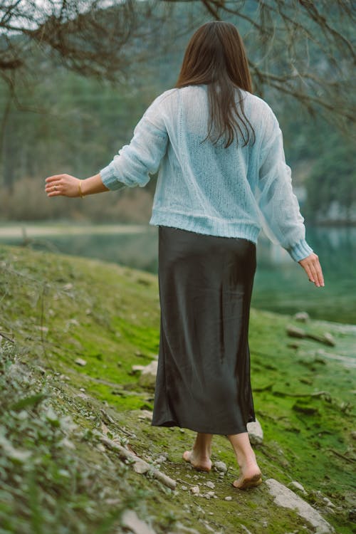 A woman in a blue sweater and black skirt walking along a path