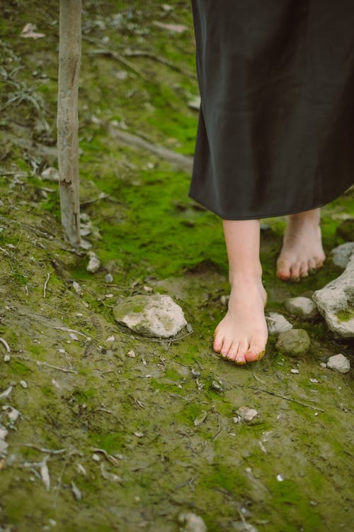 A woman's bare feet are shown in a forest