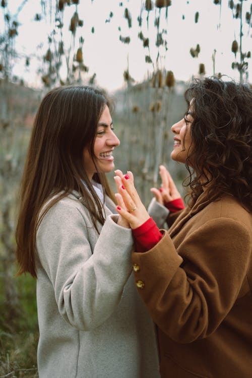 Two women are making a gesture with their hands