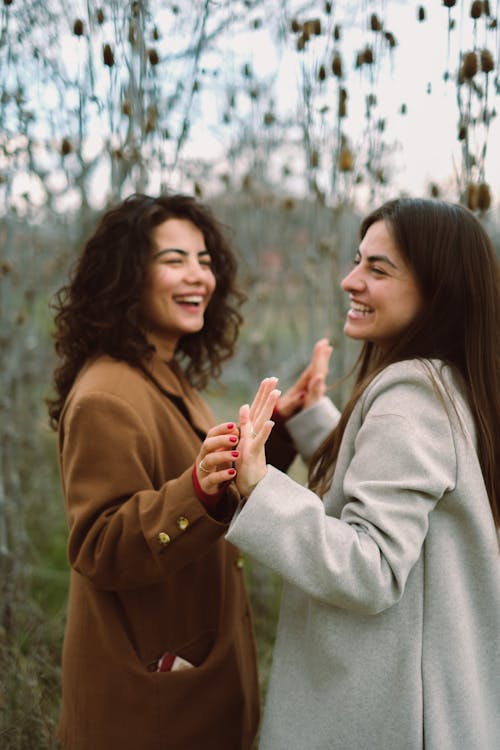 Two Women Joining Hands and Laughing