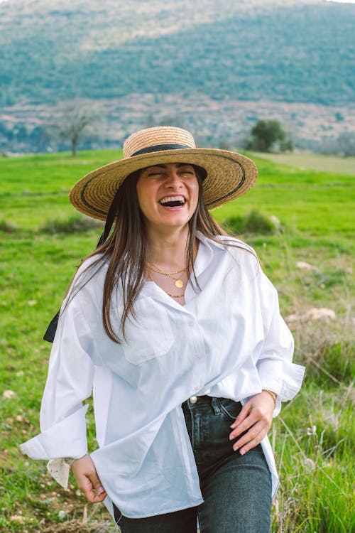 A woman in a hat and white shirt smiling