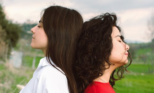 Two women standing next to each other with their heads facing each other