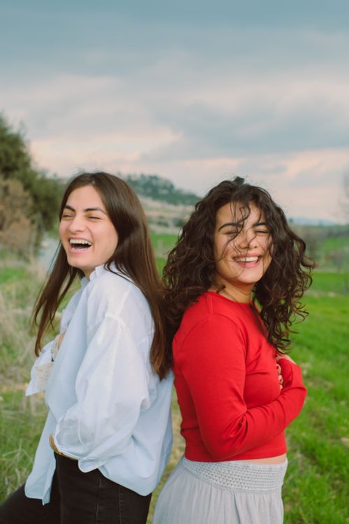 Free Two women laughing together enjoying a sunny day in a rural landscape. Stock Photo