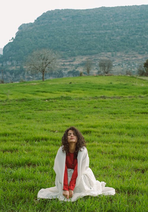 A woman sitting in a field with mountains in the background