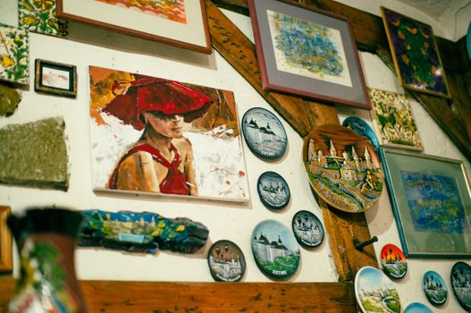 A collection of colorful paintings and decorative plates displayed creatively on a wooden wall.