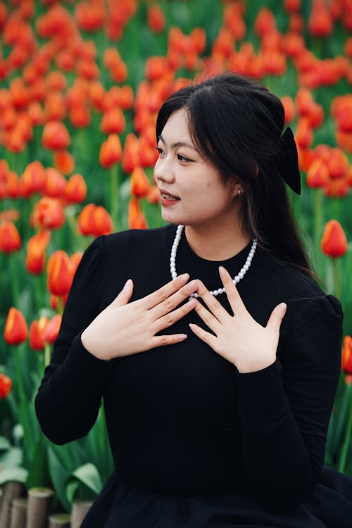 A woman in black is posing in front of tulips