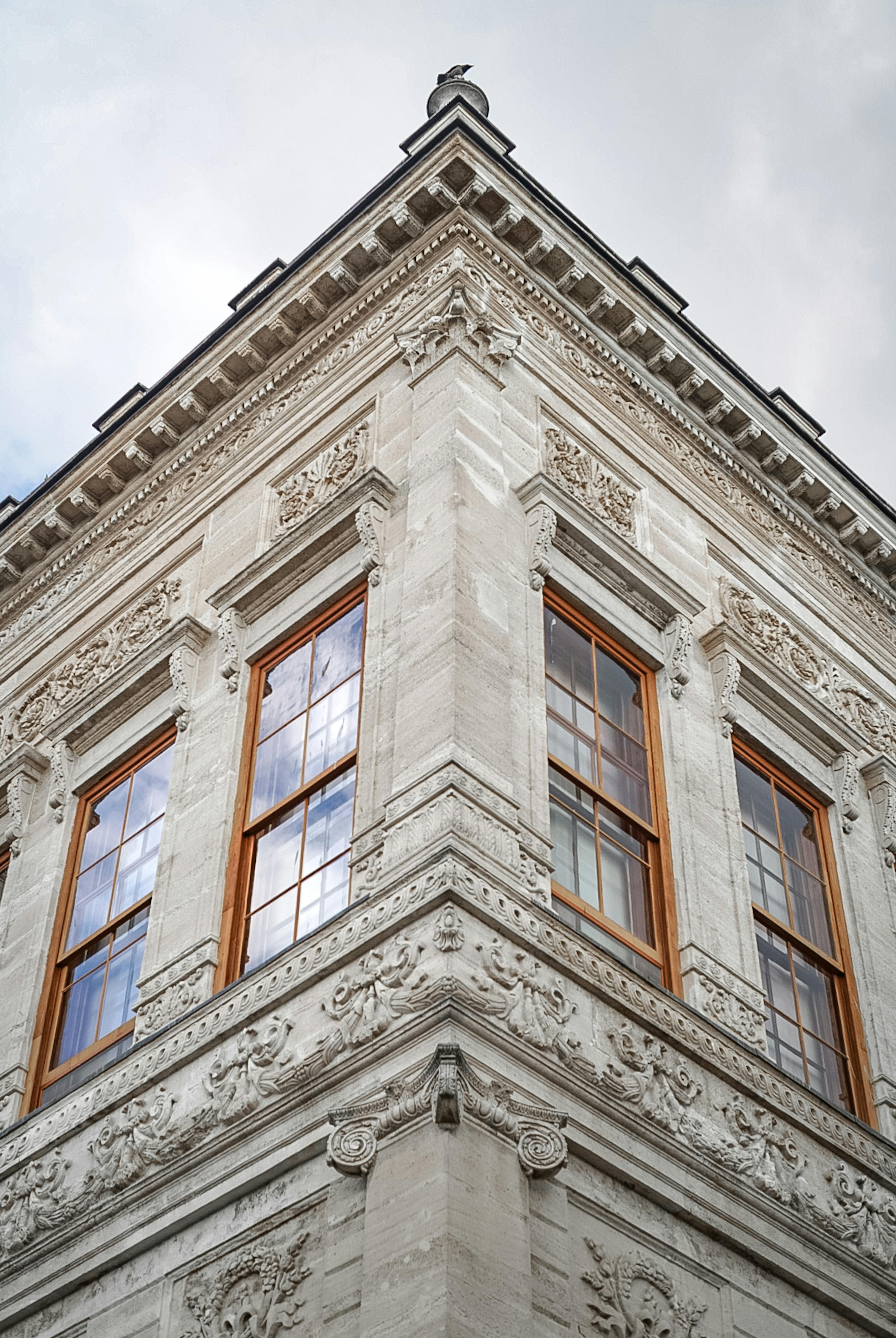 Free Corner view of an ornate vintage building with decorative windows and cloudy sky backdrop. Stock Photo