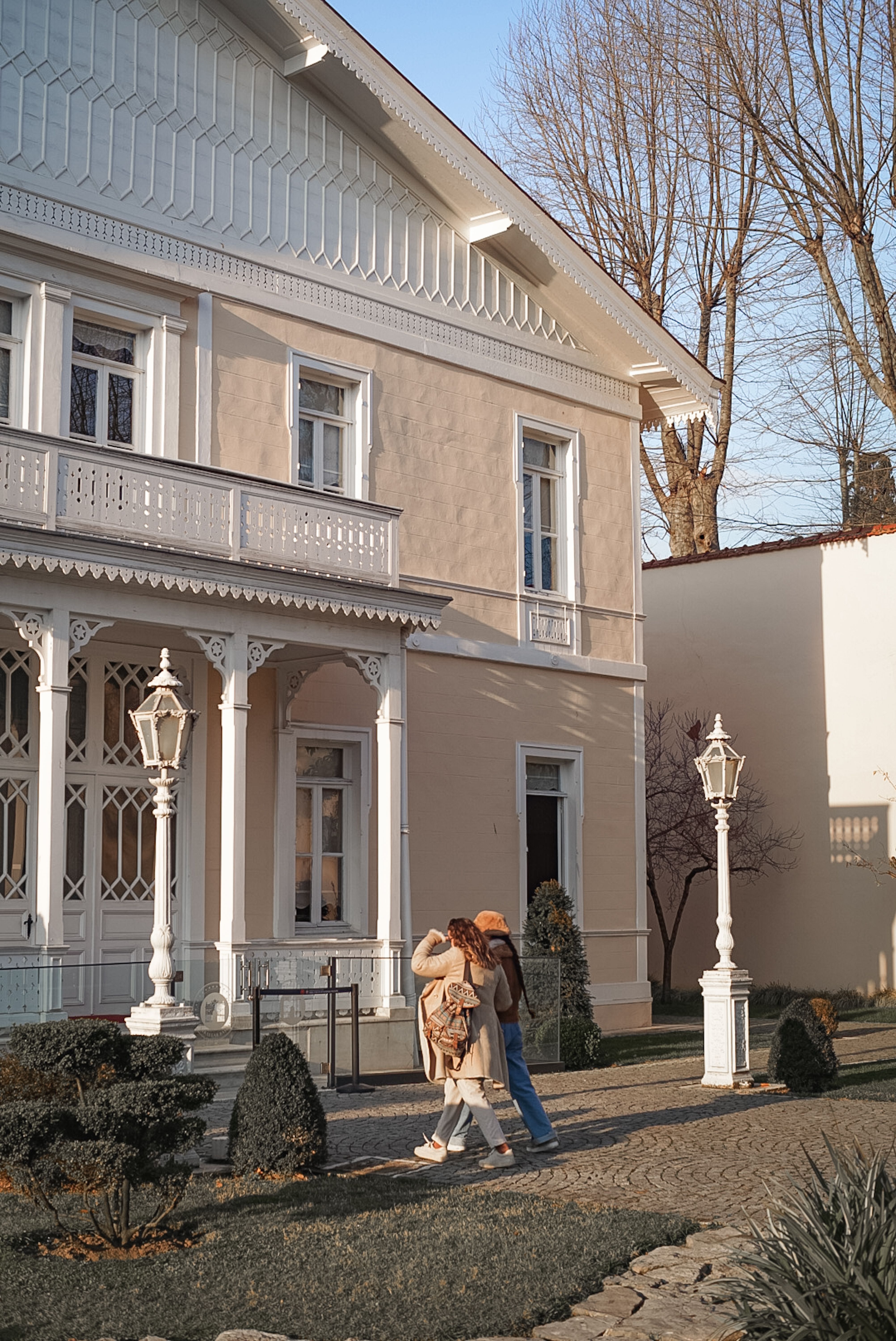 Victorian-style house with intricate details and two people walking in winter light - historic homes
