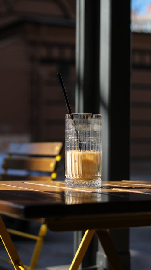 A glass of iced coffee sits on a table outside