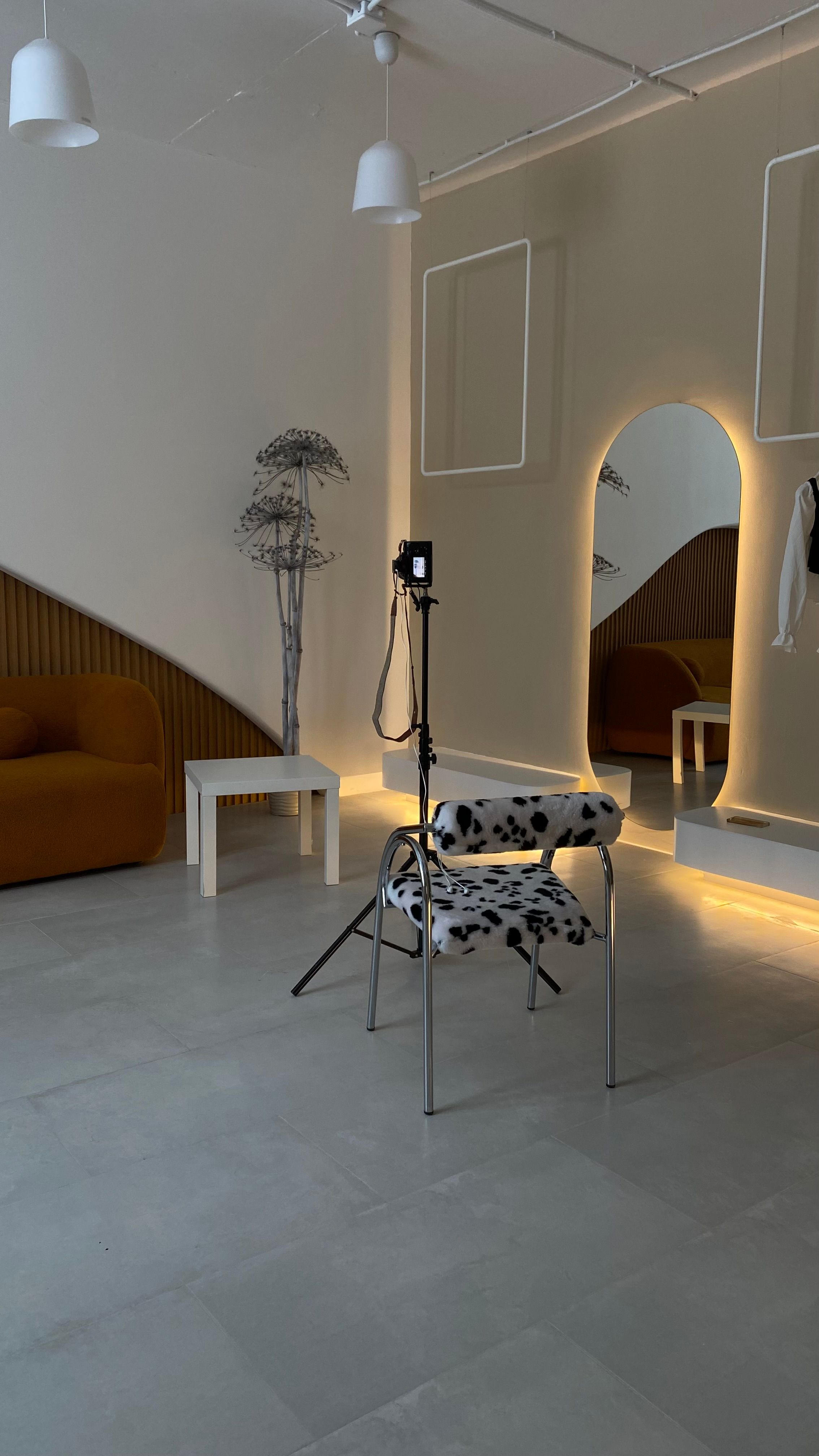 Stylish studio interior with modern furniture, including a chair and large mirror.