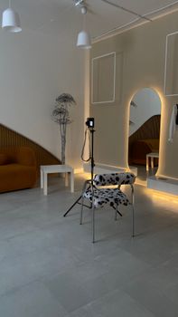 Stylish studio interior with modern furniture, including a chair and large mirror.