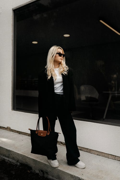 A blonde woman in black pants and a black blazer