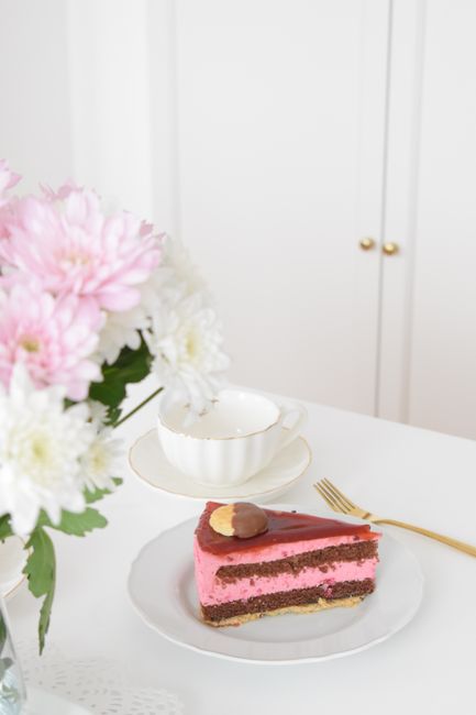 Slice of pink dessert cake on a plate with floral arrangement. Perfect for upscale dining scenes.