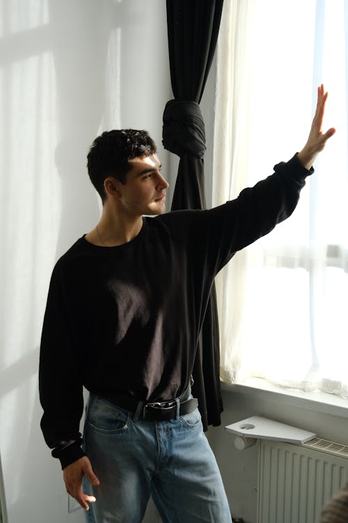 A man in jeans and a black shirt is pointing at something